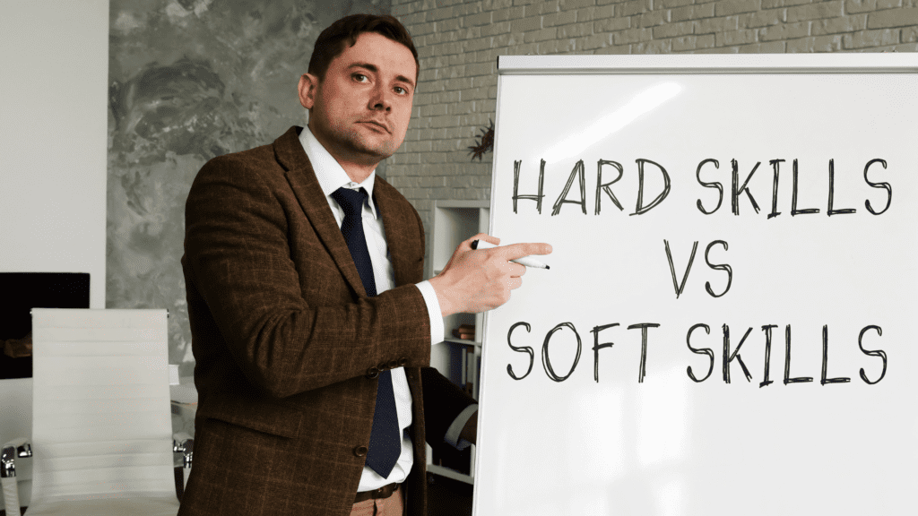 Homem branco de terno apontando para um quadro branco escrito "Hardskill VS Softskills"